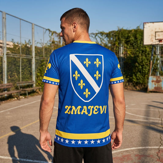 Athlete wearing Bosnia football jersey displaying bold lily symbol on outdoor sports court during day.